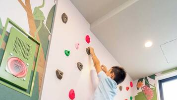 A person climbing a wall with colorful handholds.