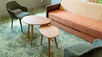 A room with a green carpet, a brown sofa, a wooden table, and a green armchair.