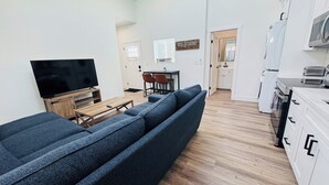 A modern apartment with a living room, dining area, and kitchen.