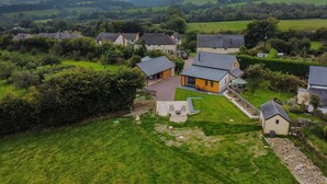 A rural village with houses, a grassy area, and rolling hills in the background. - The Chapel, Brompton Regis (Dulverton)