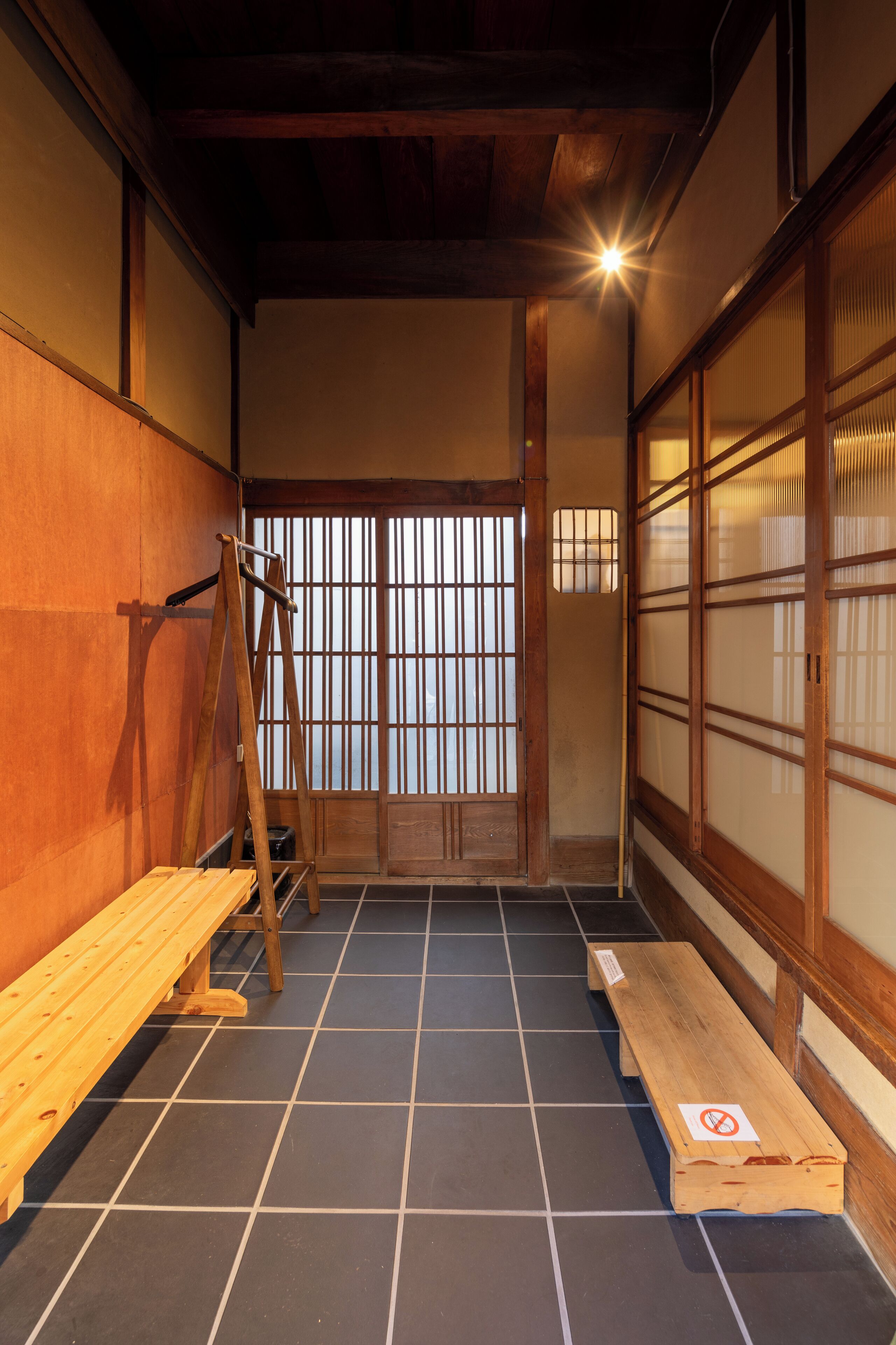 A traditional Japanese room with tatami flooring, sliding doors, and a wooden bench.
