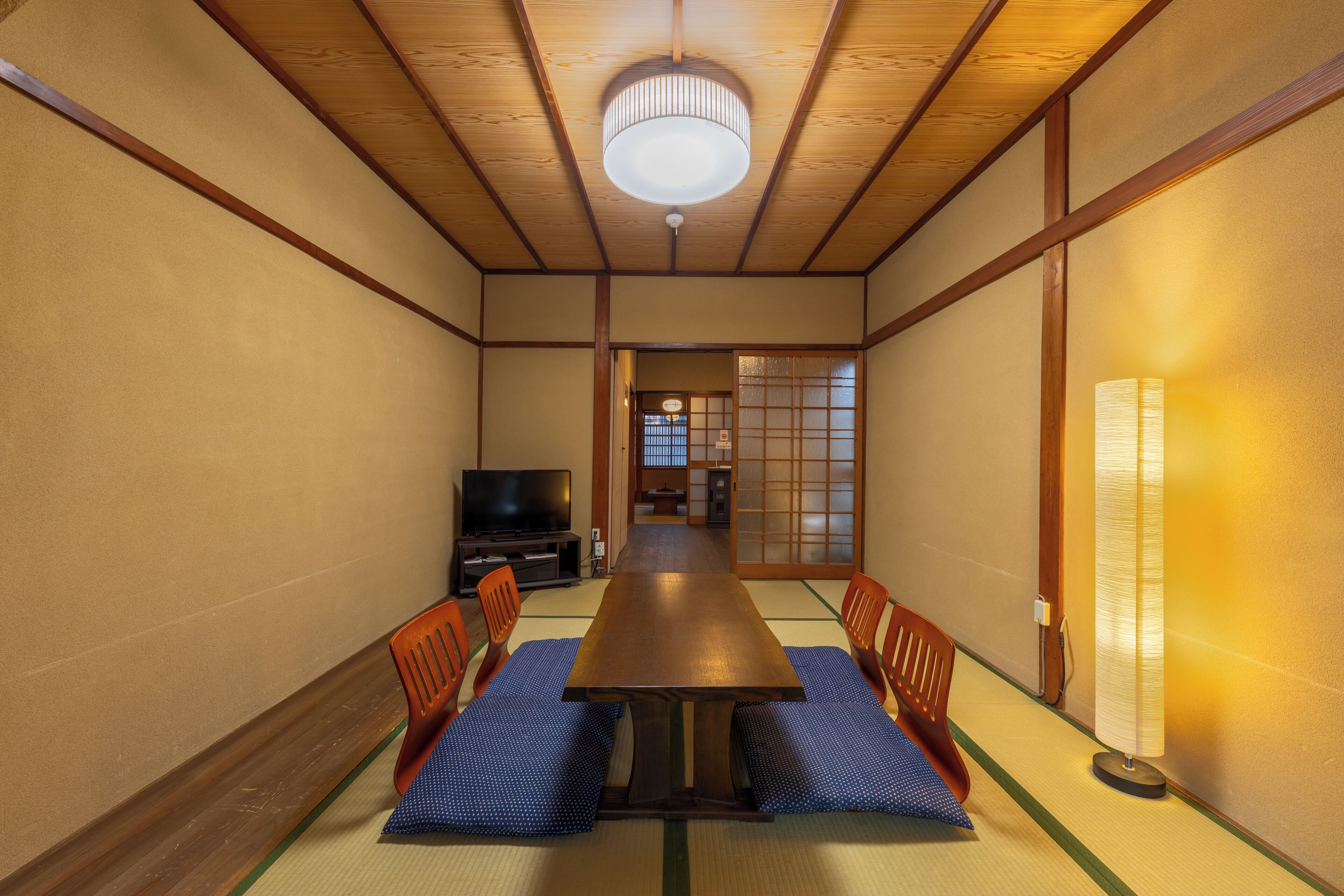 A traditional Japanese-style room with tatami flooring, a wooden table, and low wooden chairs.