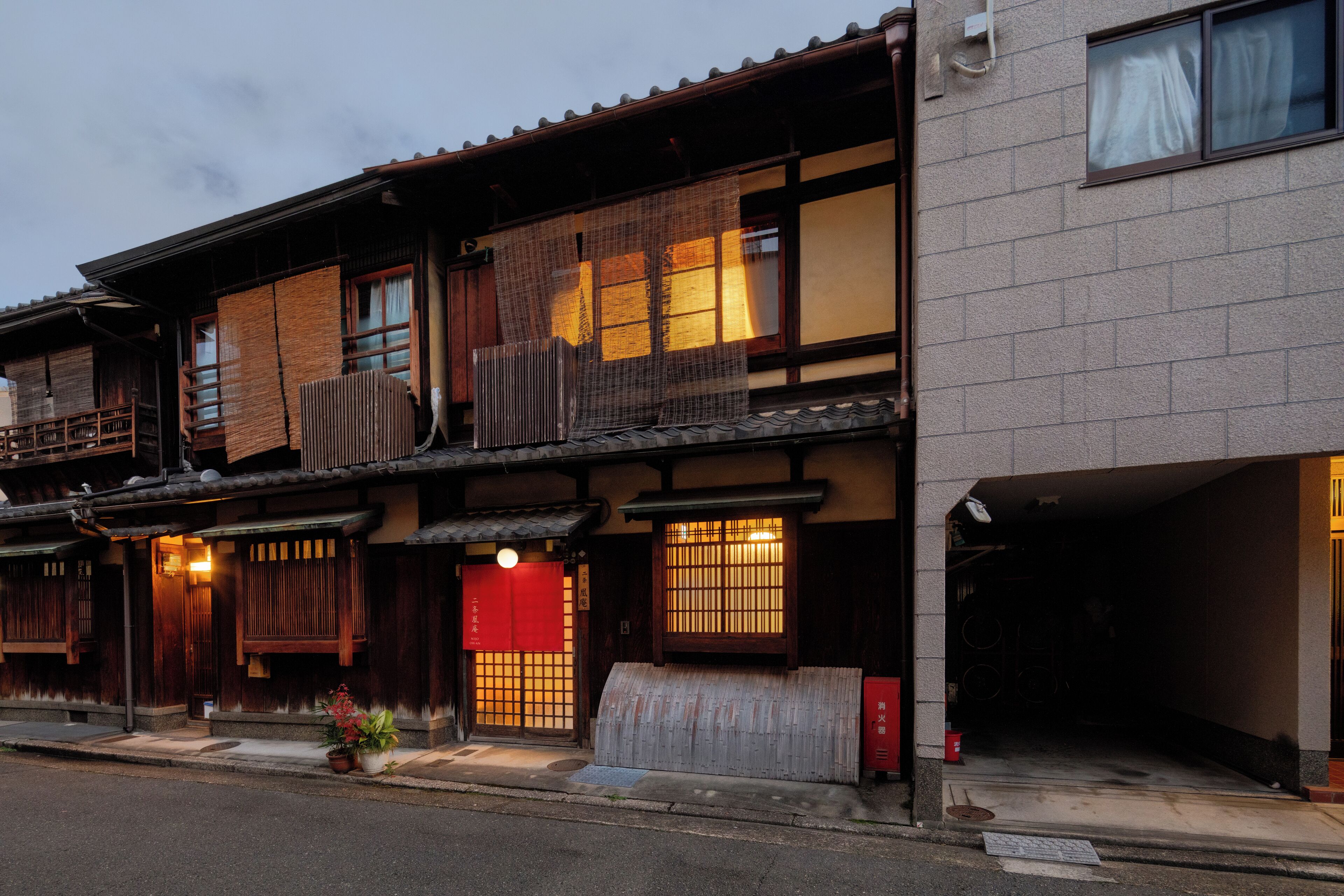 Ein traditionelles japanisches Gebäude mit Holzbeschlägen, großen Fenstern und einer roten Eingangstür.