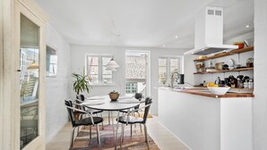Een moderne keuken met een centraal eiland, witte keukenkastjes en diverse keukenapparaten.