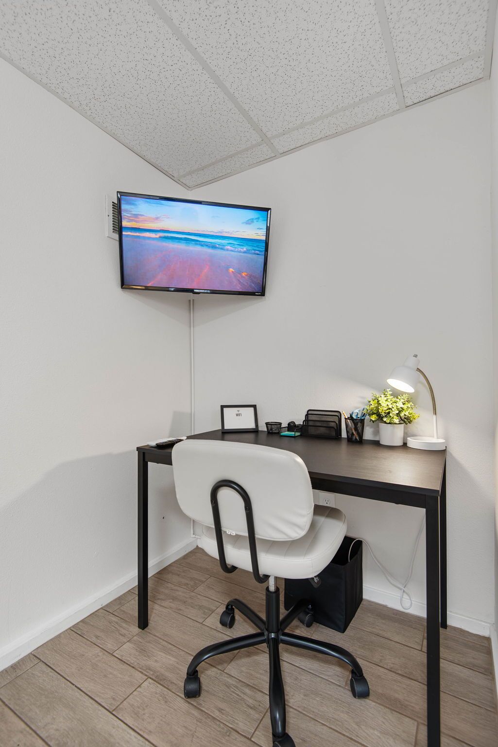 Ein moderner Arbeitsbereich mit Schreibtisch, Stuhl und einem an der Wand befestigten Flachbildfernseher.