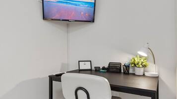 Ein moderner Arbeitsbereich mit Schreibtisch, Stuhl und einem an der Wand befestigten Flachbildfernseher.