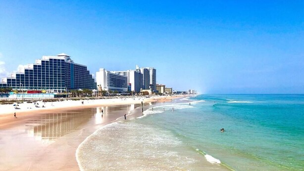 Ein Strand mit einem Hotel im Hintergrund.