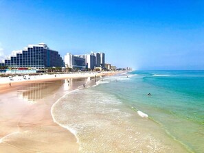 A beach with a hotel in the background.