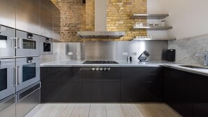 Una cocina moderna con electrodomésticos de acero inoxidable, una isla central y una pared de ladrillo.