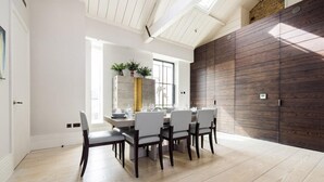 Un comedor con mesa y sillas de madera, un ventanal grande y un panel de pared moderno.