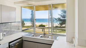 Una cocina moderna con un ventanal grande que da a una playa.