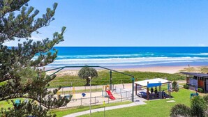 Un parque infantil en la playa con toboganes y una zona de descanso cubierta, con vistas al océano.