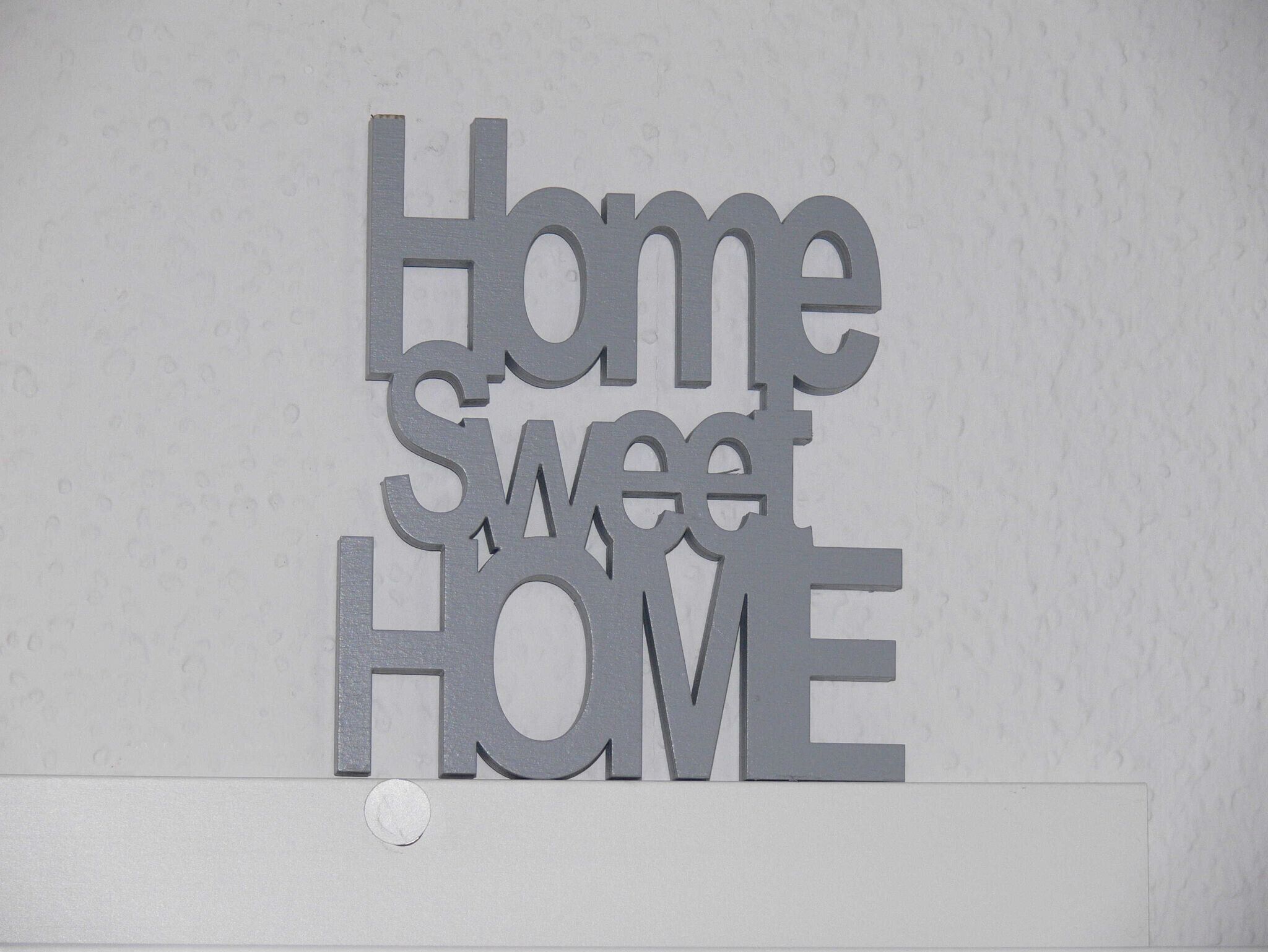 A wall decoration with the words 'Home sweet HOME' in a metallic finish.