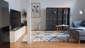 Una sala de estar moderna con televisor, sofá, estantería y adornos decorativos.