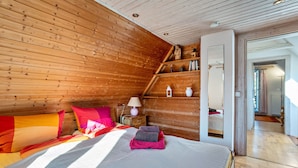 Una habitación con paneles de madera, una cama, almohadas, una mesita de noche y una lámpara.
