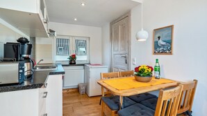 Una cocina compacta con electrodomésticos modernos, un comedor con mesa y sillas de madera, y vistas de la habitación contigua.
