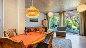 A dining area with a wooden table, chairs, and a hanging light fixture.