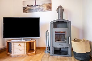 Ein Wohnzimmer mit Flachbildfernseher, einer Holzeinrichtung und einem Kaminofen.