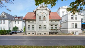 A large, historic building with a symmetrical facade, multiple windows, and a red-tiled roof.