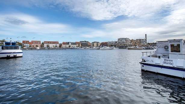 A waterfront view with boats, a marina, and buildings in the background.