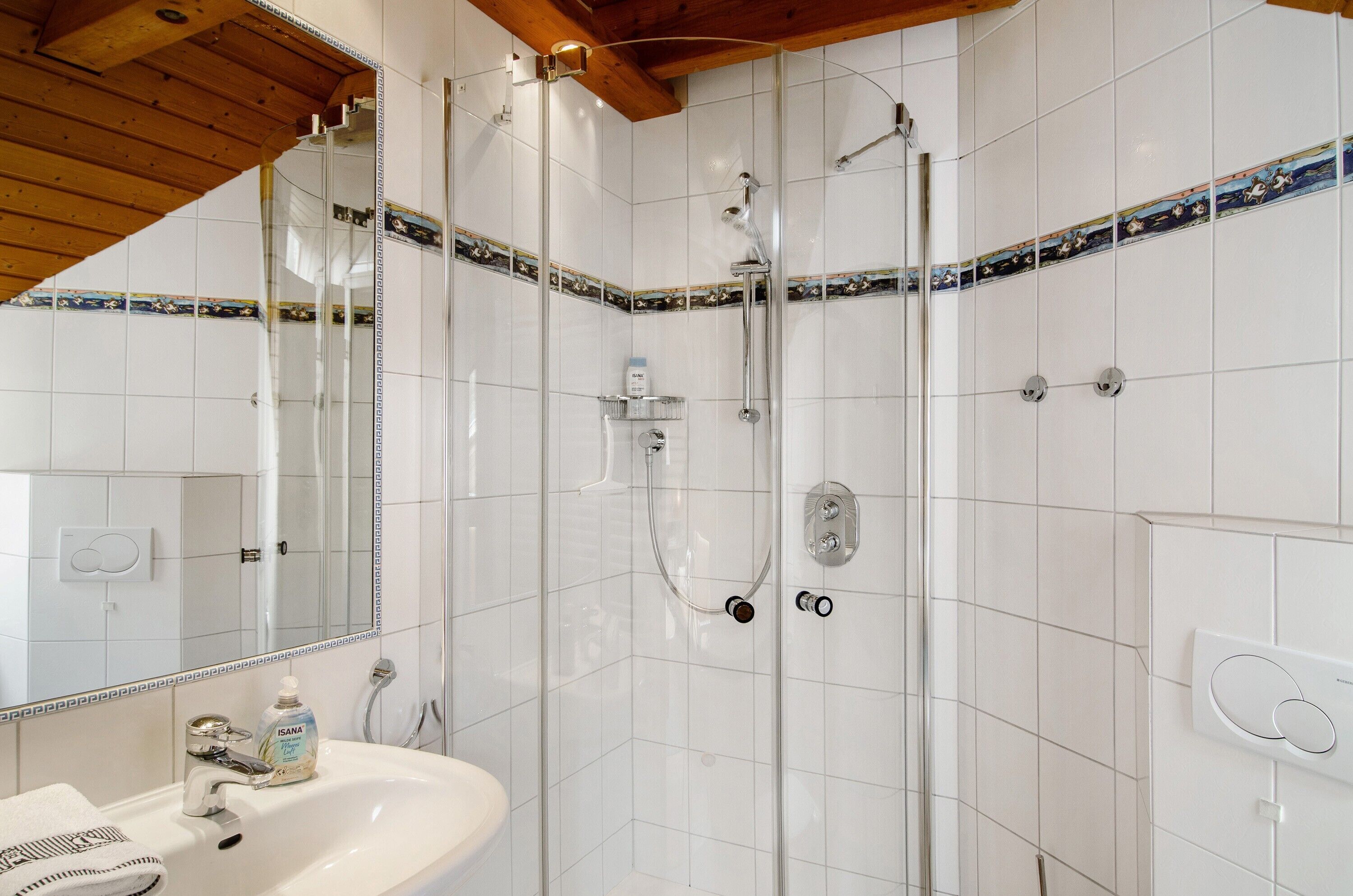 Un bagno con doccia, lavandino e specchio.