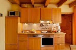 A kitchen with wooden cabinets, stainless steel appliances, and a hanging utensil rack.