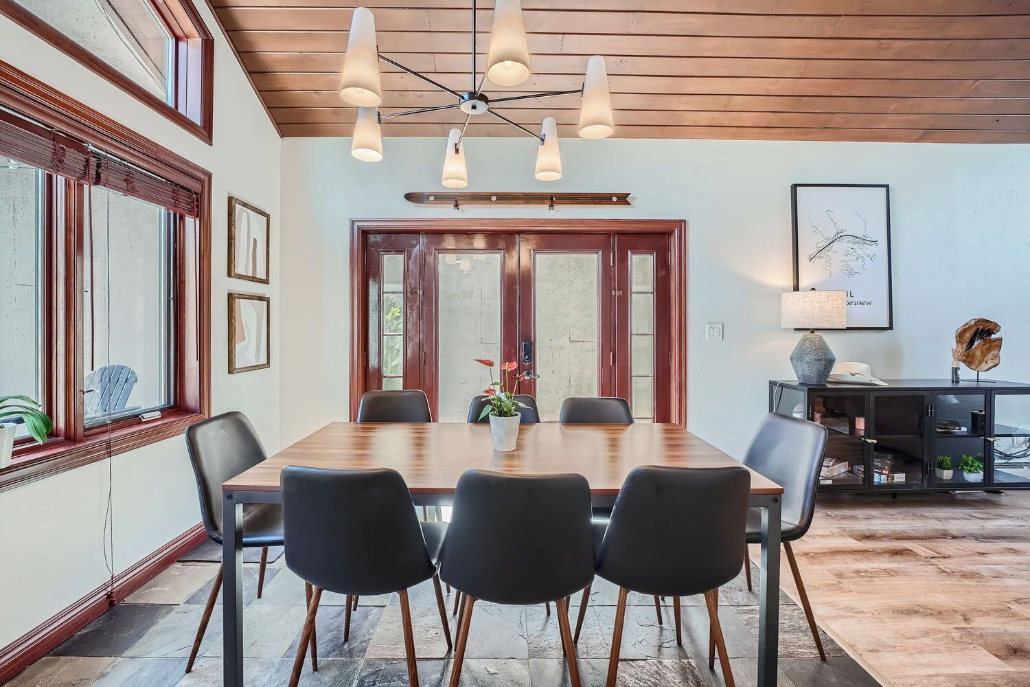 A dining area with a wooden table, black chairs, and a ceiling light fixture.