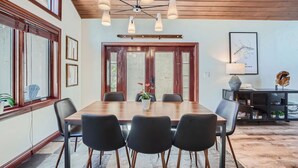A dining area with a wooden table, black chairs, and a ceiling light fixture.
