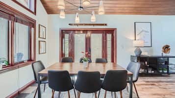 A dining area with a wooden table, black chairs, and a ceiling light fixture.