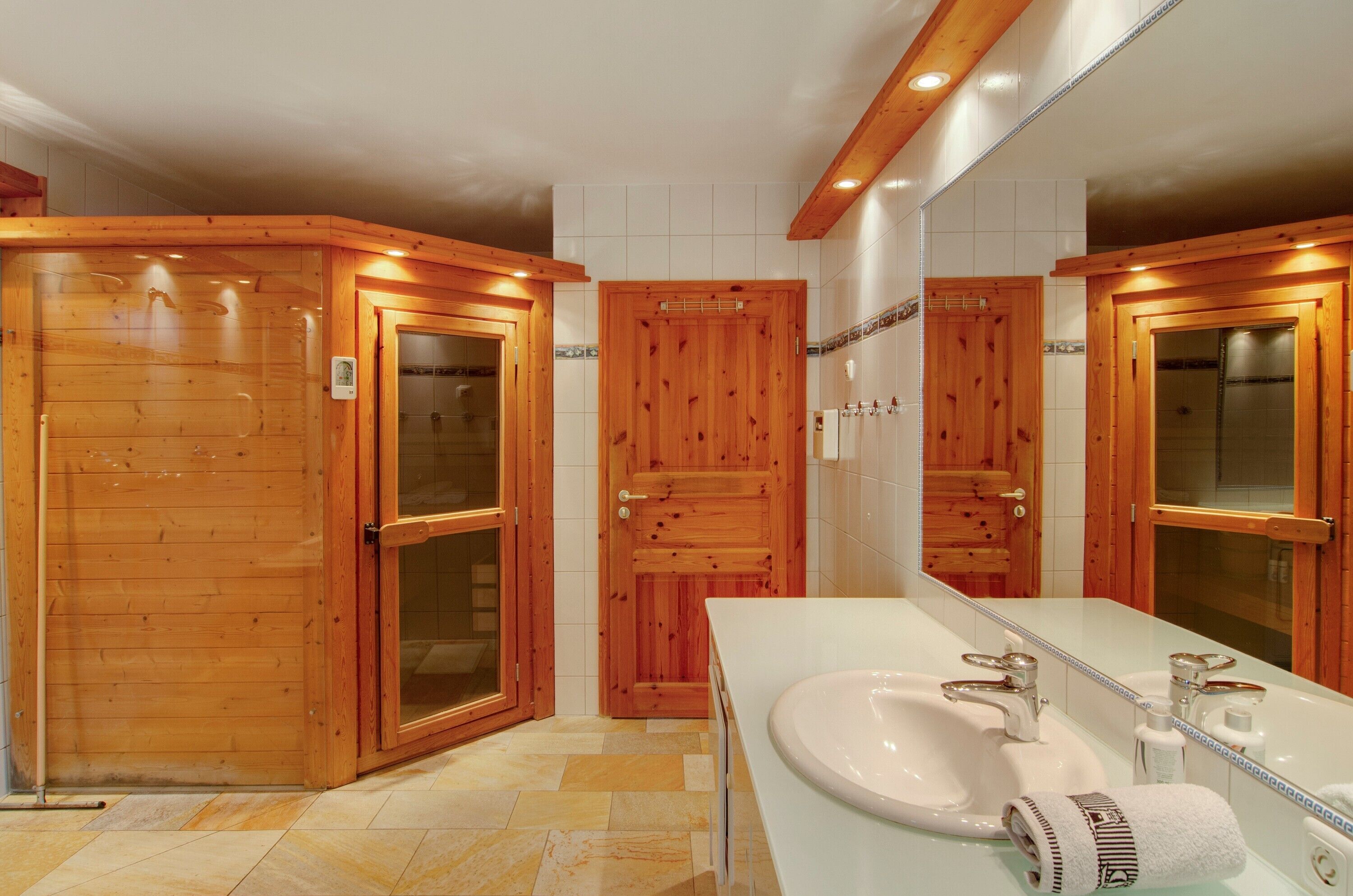 Ein Badezimmer mit Holzausstattung, einem weißen Waschbecken und einem Spiegel.