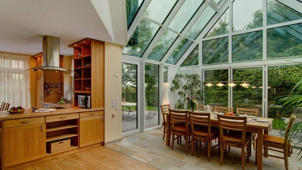 Una cocina moderna con armarios de madera, estufa empotrada y comedor con mesa y sillas.