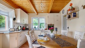 A kitchen with white cabinets, a wooden ceiling, and a dining table with chairs.