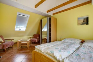 A bedroom with a bed, a chair, a table, and a window.