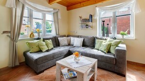 A living room with a grey sectional sofa, a wooden coffee table, and a bookshelf.