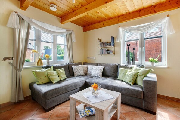 A living room with a grey sectional sofa, a wooden coffee table, and a bookshelf.
