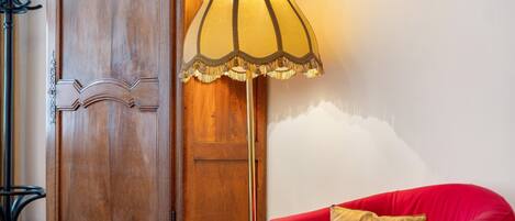 A room with a wooden cabinet, a floor lamp, and a red sofa.