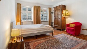 A bedroom with a bed, a red chair, a wooden wardrobe, a lamp, and a patterned rug. - Apartment 'Ferienwohnung Nr 3' with Shared Terrace, Shared Garden and Wi-Fi (Lychen)