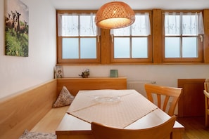A dining area with a wooden table, chairs, a woven pendant light, and a window with a view of the countryside. - Apartment 'Talblick' with Shared Terrace, Shared Garden and Wi-Fi (Horben)