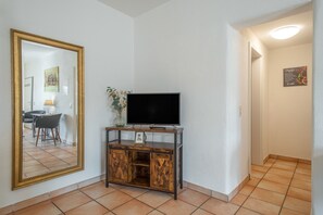 Habitació amb televisió sobre un moble de fusta, un mirall gran i un quadre al mur.