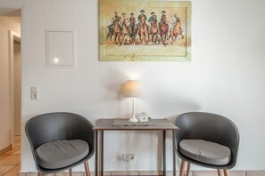 Una habitación con dos sillas negras, una mesita, una lámpara y un cuadro en la pared.