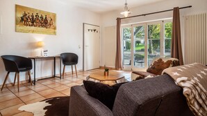 A living room with a sofa, a coffee table, a painting, and a door leading to a balcony.
