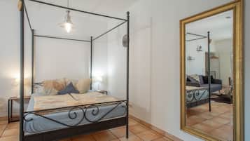 Ein Bett mit Himmelbett, ein Nachttisch mit Lampe und ein großer Spiegel an der Wand.