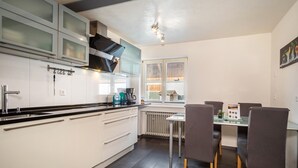 Una cocina moderna con armarios blancos, encimera negra y un comedor con mesa y sillas.