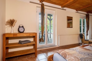 A room with a bed, a wooden console table with a clock, a radiator, and a window with a view of trees. - Apartment 'Ferienhäuschen' with Private Terrace, Shared Garden and Wi-Fi (Ravensburg)