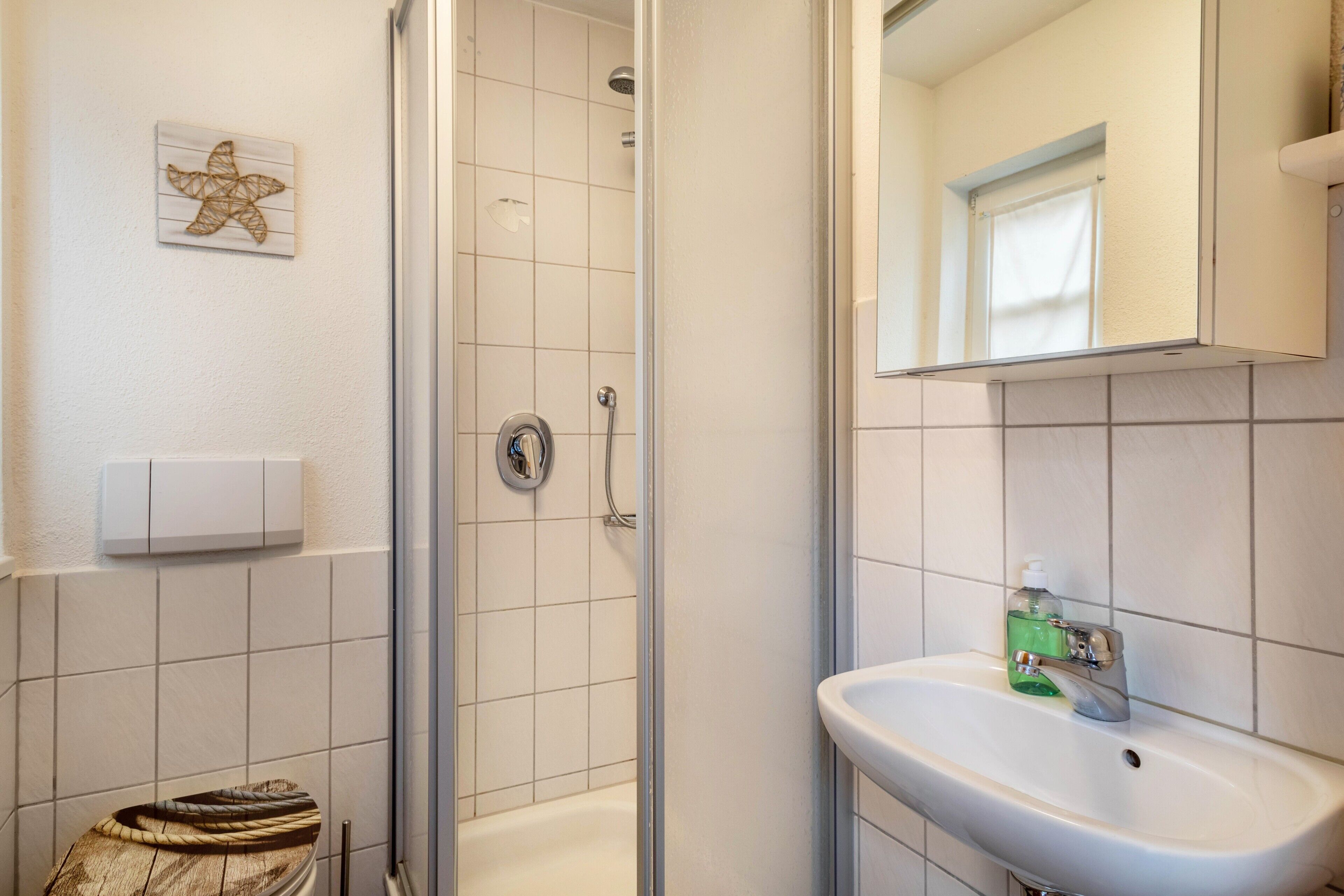 Ein Badezimmer mit Dusche, Toilette, Waschbecken und einem dekorativen Seestern an der Wand.