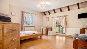 Un dormitorio con una cama y cómoda de madera, una mesita de noche, un televisor y una ventana con cortinas.