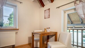 Una habitación con una mesa de madera, una silla blanca, un radiador y una ventana con vistas.