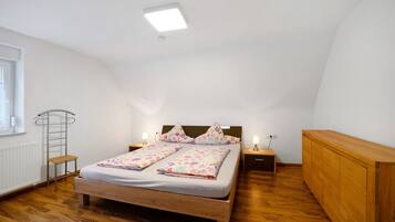 A bedroom with a wooden bed, a nightstand, a dresser, a radiator, and a window.