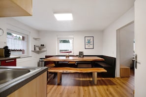 Een keuken met een houten bankje, een eettafel en een raam met uitzicht.