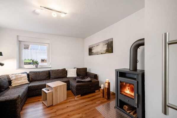 Una sala de estar moderna con un sofá modular, una mesa de centro de madera, una chimenea y un ventanal con vistas.